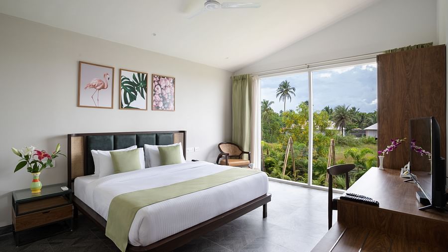 full view image of the bedroom at the ocean suite with ample of natural light featuring a king size bed along with an elegant french window at the far end of the bedroom