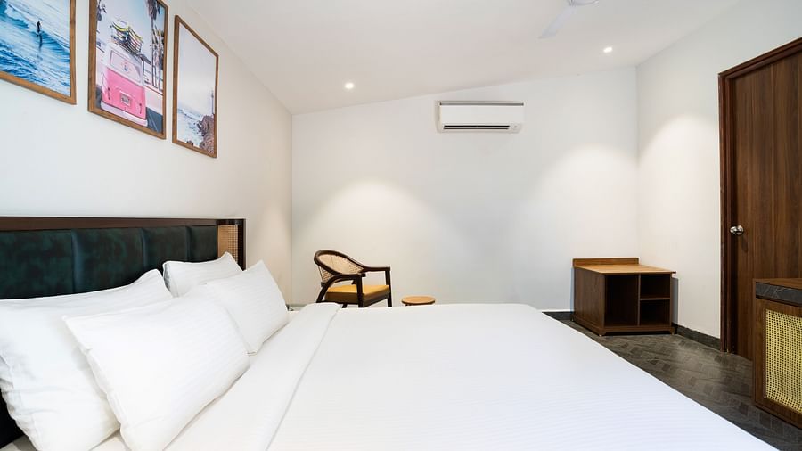 image of a queen size bed with white sheets spreak over ti with an arm chair in the far end of the room