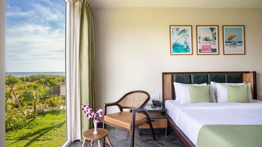 image of the ocean suite that features a queen size bed along with an arm chair with beautiful views from the window besides it