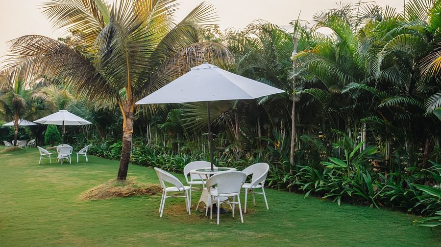 image featuring a seating area with four chairs with a white coloured umbrella providing shade to it
