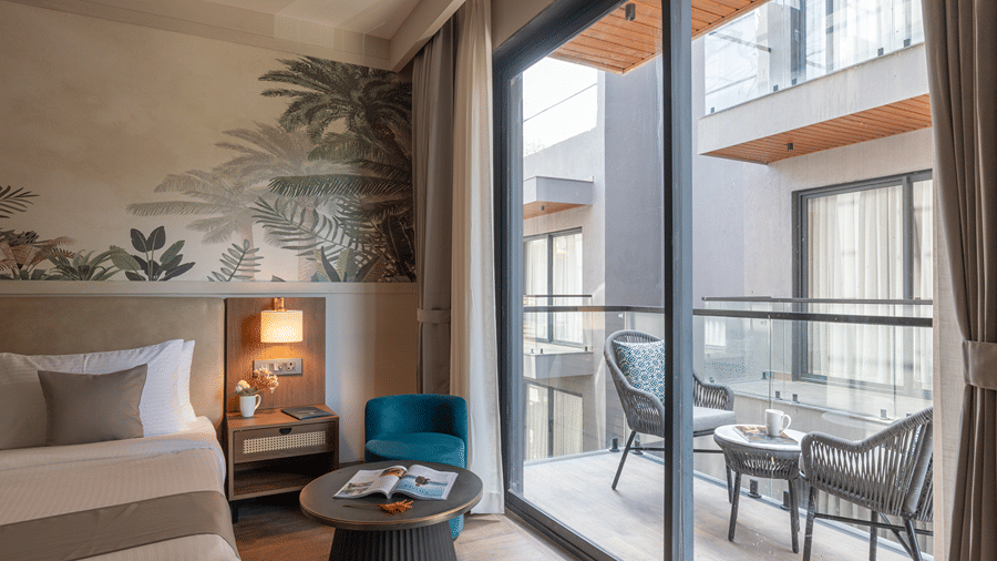 Hotel room lounge area with sliding glass doors opening onto a balcony with pool views.