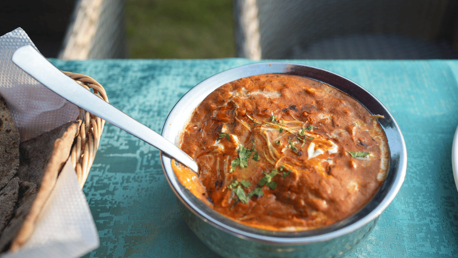 A creamy Indian dish in a metal serving bowl with a spoon | Sol Glow Resort, Nainital