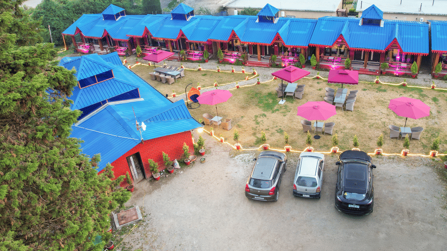 Aerial view of Sol Glow Resort, Nainital showing cars parked in parallel, facing cottages placed side to side.
