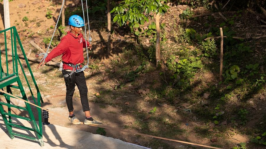 Image of a person navigating a high rope course wearing safety gear. | Stone Wood Jungle Resort, Dandeli