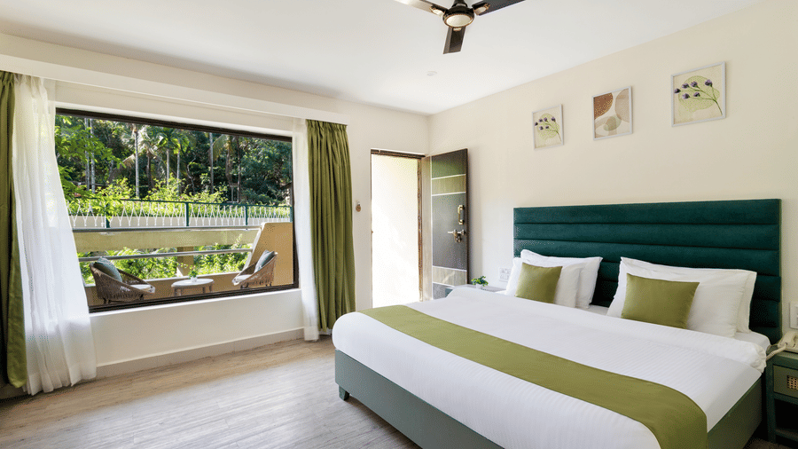 Bright and airy bedroom overlooking greenery at Stone Wood Premier Dandeli, featuring modern comforts and serene views.