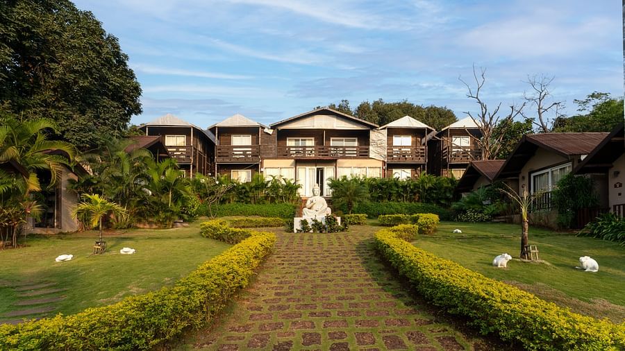 Lush garden with resort villas and statues at Stone Wood Resort, Mandrem