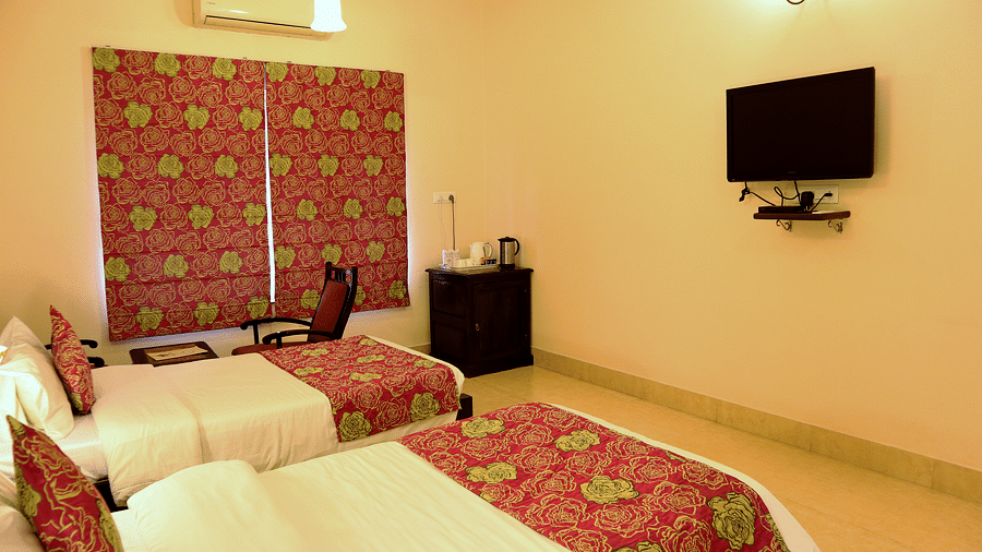 Television and Twin beds with beautiful red bedsheets and red pillow covers at Junior Suite at Suryaa Villa Jaipur