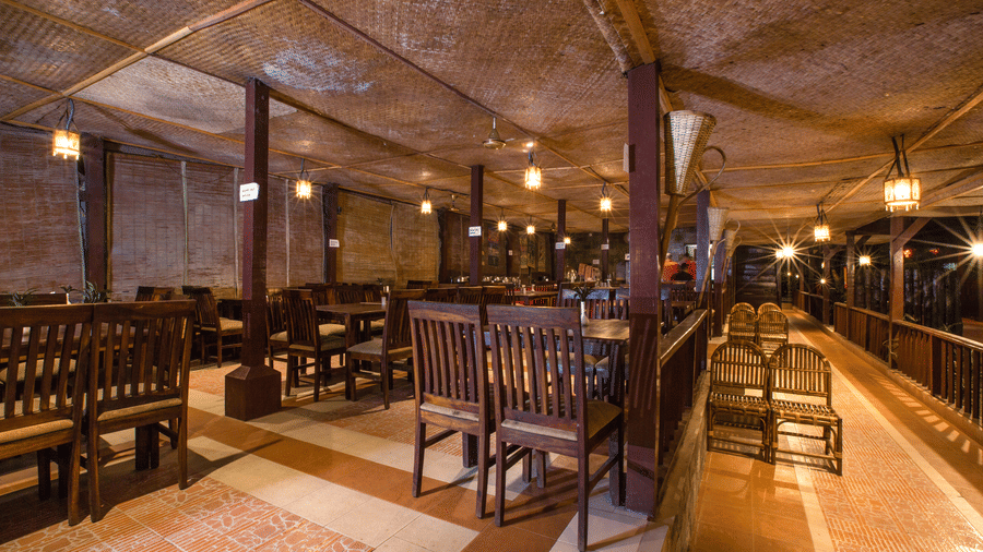 The Charcoal Restaurant, one of the best places to eat in Havelock, featuring a neatly arranged and illuminated dining area with wooden and cane chairs.