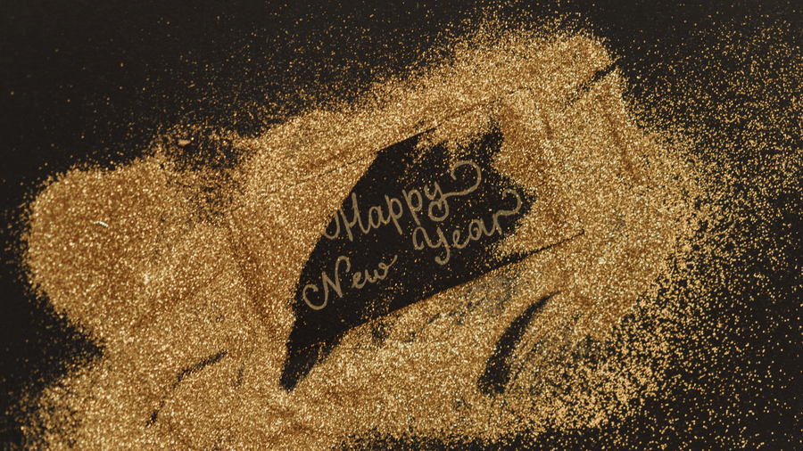 'Happy New Year' written in gold glitter on a dark background.