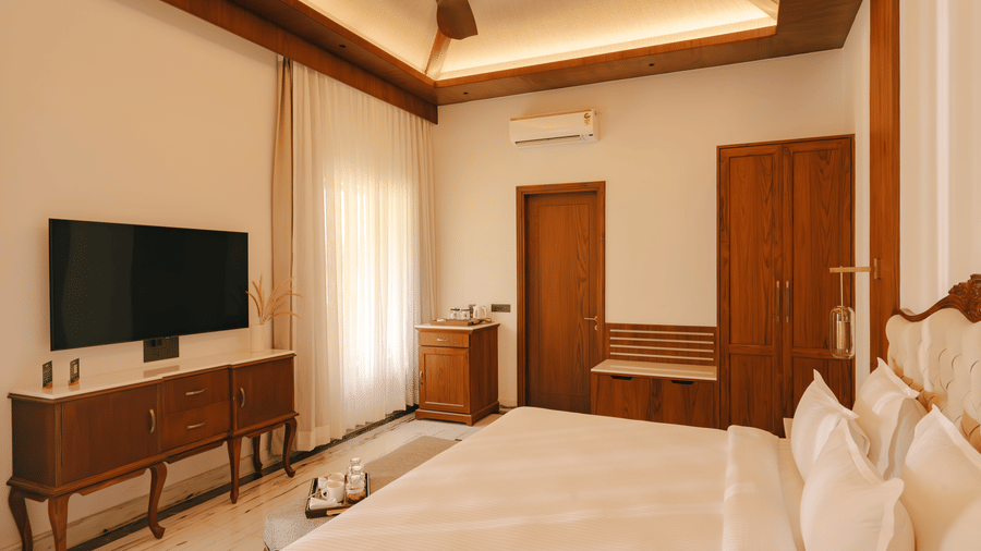 Comfortable bed facing a TV above a cabinet at The Ananta Udaipur.