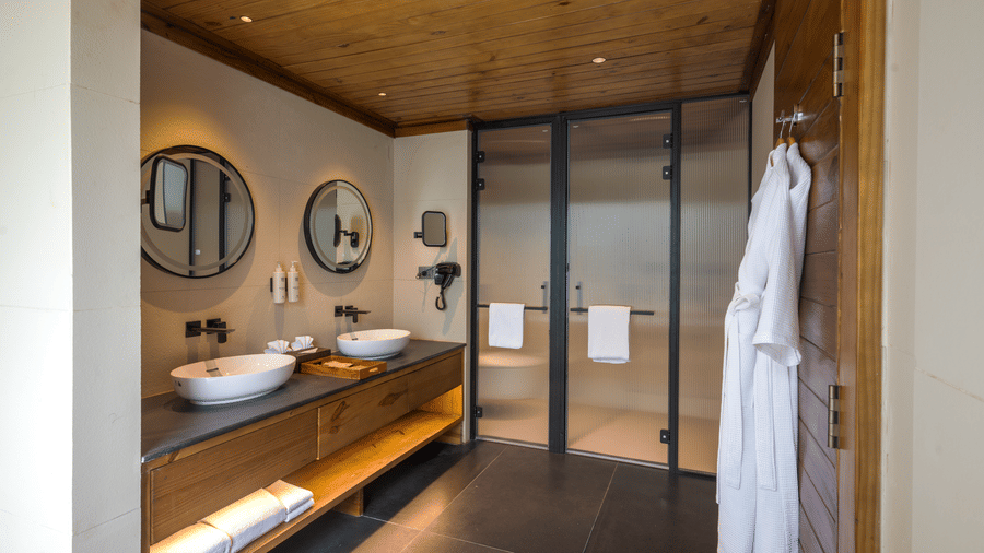 A bathroom at The Ananta Udaipur, with a sink, bathrobe, and mirrors.