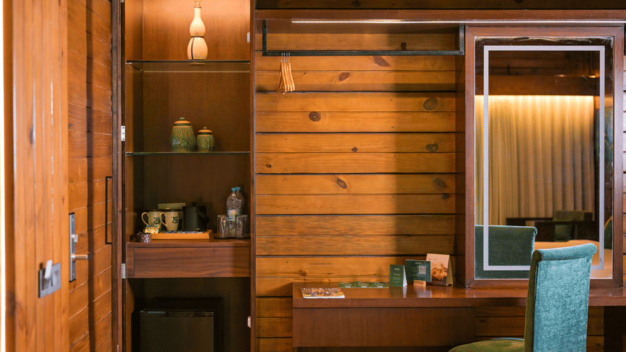 A room at The Ananta Udaipur, featuring wooden wardrobes, a mirror, and toileteries.