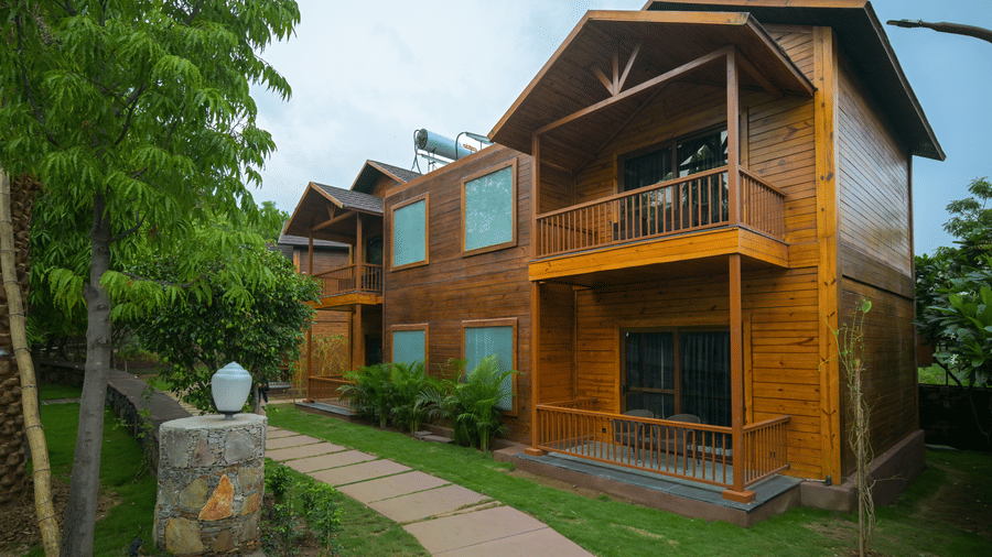 The Ananta Udaipur | The wooden facade with multiple windows, doors, and plants in the front.