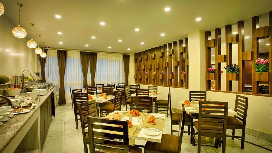 full view of indoor restaurant with table and chair along with buffet table - the aryan regency