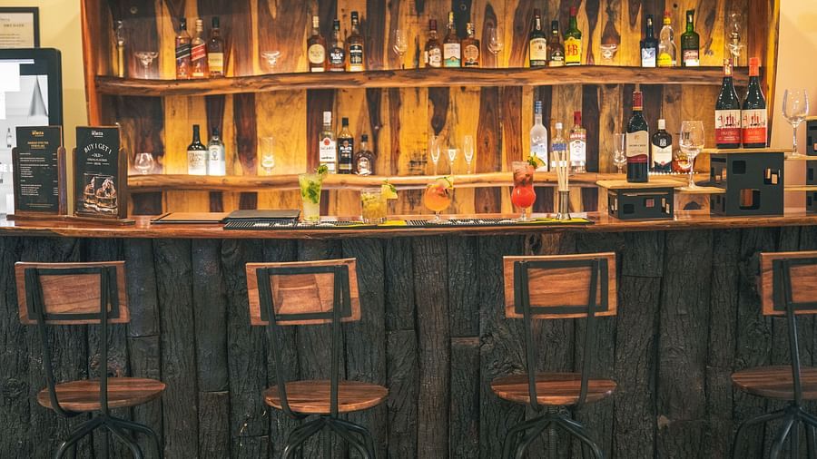 Bar counter with various alcohol bottles displayed and chairs placed in front of the counter
