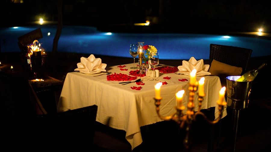 Beautiful table set up with candle lights and rose petals near swimming pool