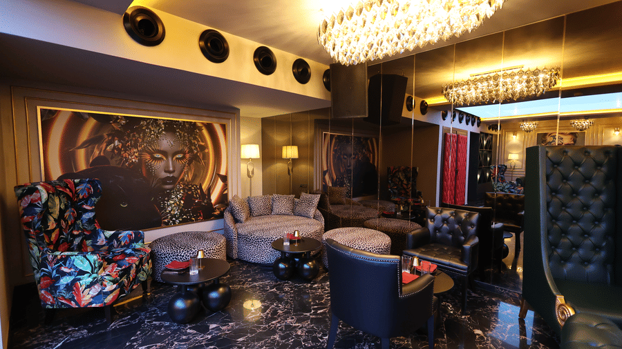 Richly decorated lounge at The Beatle Hotel, Powai. Plush dark seating, a large circular chandelier, and contemporary art on the walls.