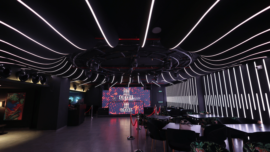 Dark club interior at The Beatle Hotel, Powai. Dramatic ceiling and wall lighting with white LED strips, overlooking tables and a screen.