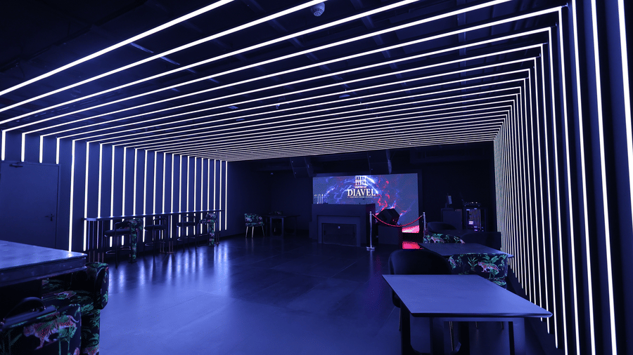 Interior of a club space at The Beatle Hotel, Powai. Blue-white linear LED lights create converging lines on the ceiling and walls.