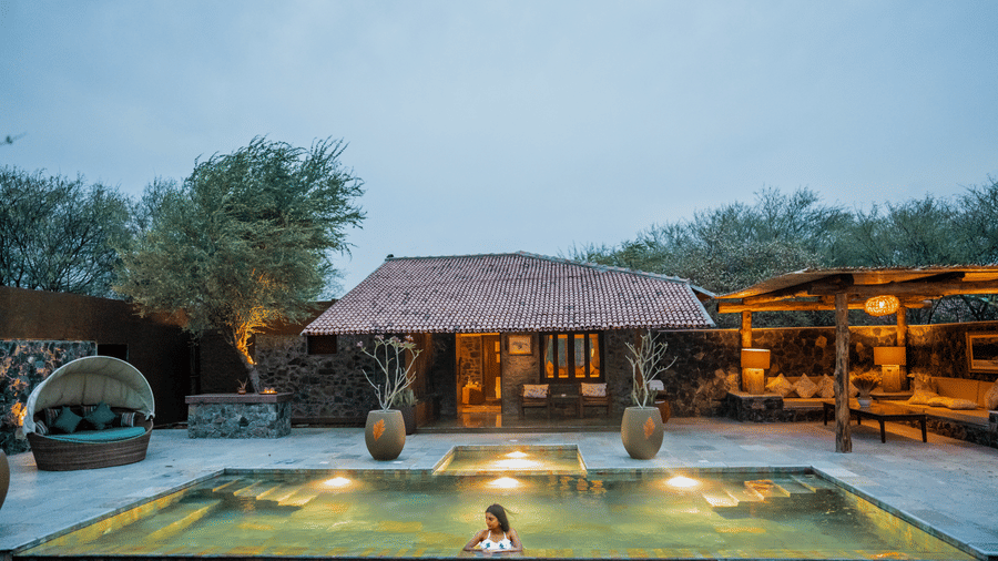 Swimming pool of The Blackbuck Lodge, Velavadar featuring a cottage and evening lighting.