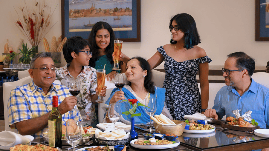 A family enjoying their food at Clarks Hotels with multiple dishes placed on a table infront of them.