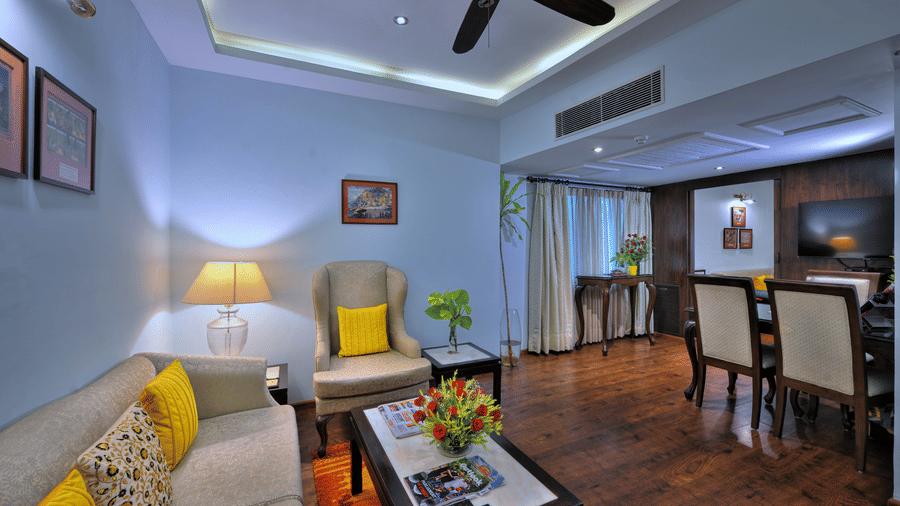 A room with a fan, chairs, sofa, a table, and windows. | Clarks Varanasi