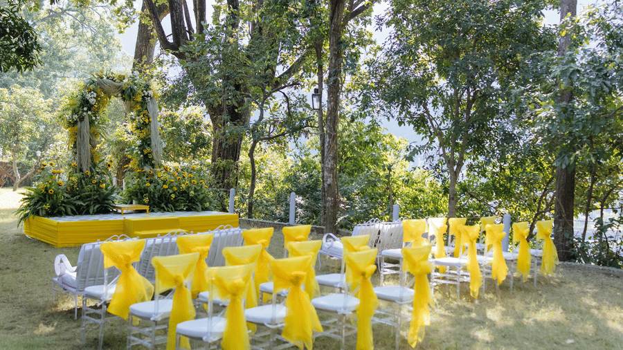 An event space at The Den Corbett Resort, with a decorated seats, trees, and plants.