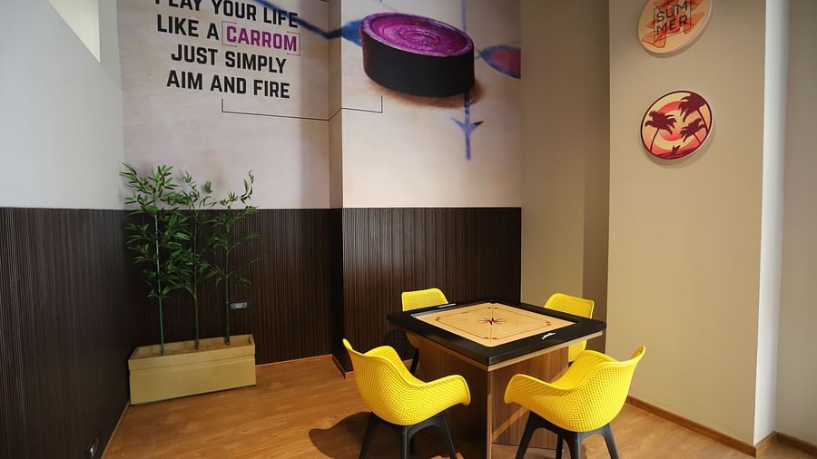 A lounge at The Gaurs Sarovar Premiere, with comfortable chairs and table along with Carrom board.