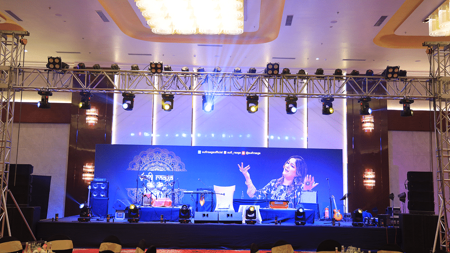 A large event hall at The Gaurs Sarovar Premiere with a stage, lighting, and an audience seated at tables.