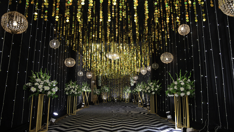 A decorated hallway at The Gaurs Sarovar Premiere with hanging decorations, floral arrangements, and a patterned floor.