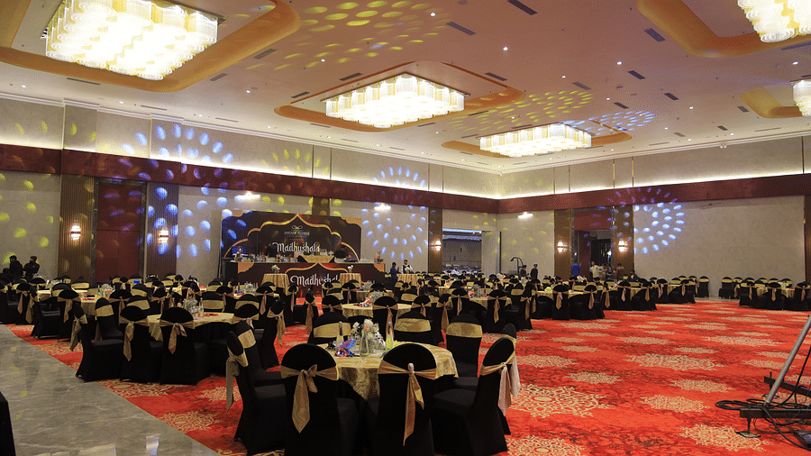 An interior shot of a banquet hall at The Gaurs Sarovar Premiere with round tables and chairs set for an event.