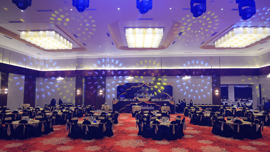 An interior shot of a banquet hall at The Gaurs Sarovar Premiere with purple lighting and round tables set for an event.