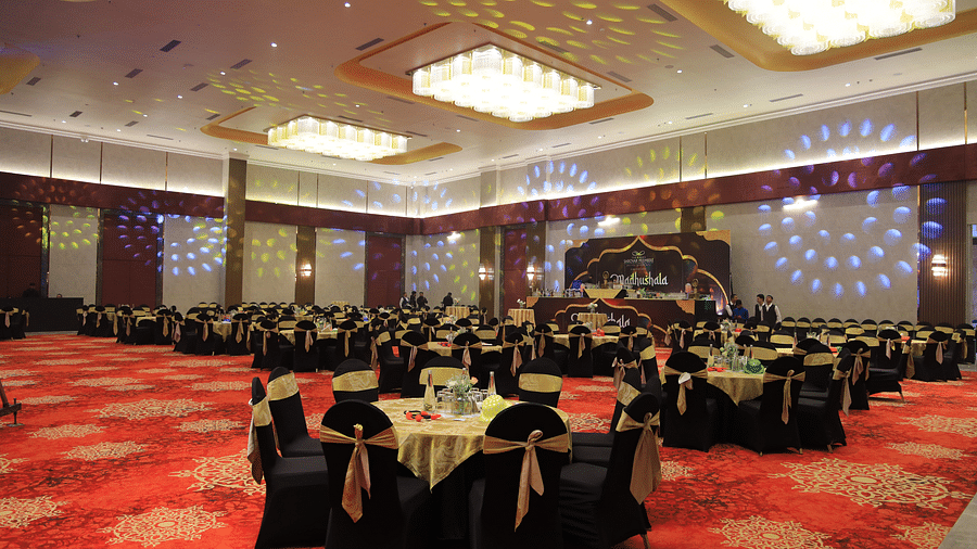 A banquet hall at The Gaurs Sarovar Premiere with red carpets, round tables, and chairs set for an event.