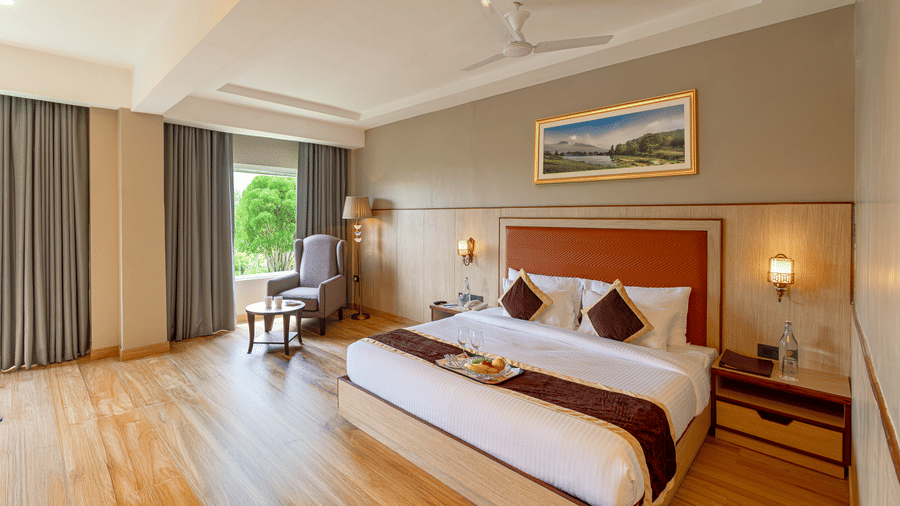 Elegant room at The Lalita Grand Mathura - Vrindavan with a king size bed, wooden flooring, large window views, and refined contemporary decor.