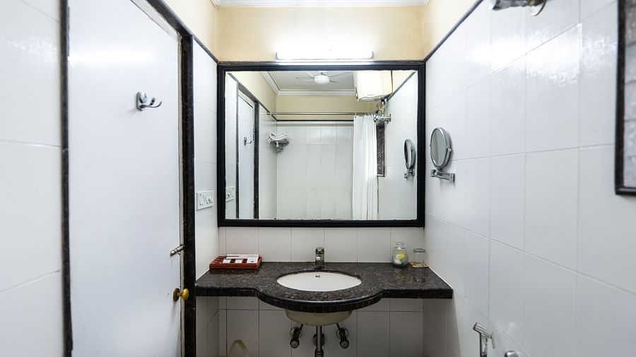 An image of a bathroom that has a sink, faucet, toiletries, and a mirror on the wall - The Lindsay