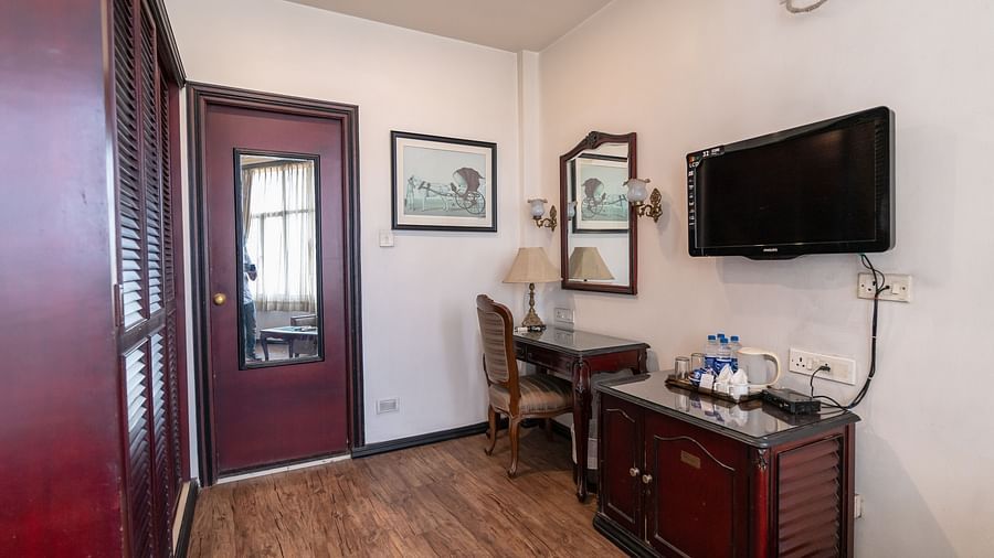 An image of a well-furnished room that has a table, a cupboard, and a flat TV Screen - The Lindsay