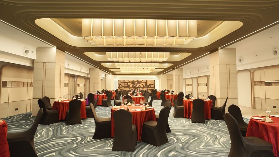 Event hall with round tables draped in red, surrounded by black chairs. Neutral walls and patterned flooring - The Orchid Hotel, Chandigarh