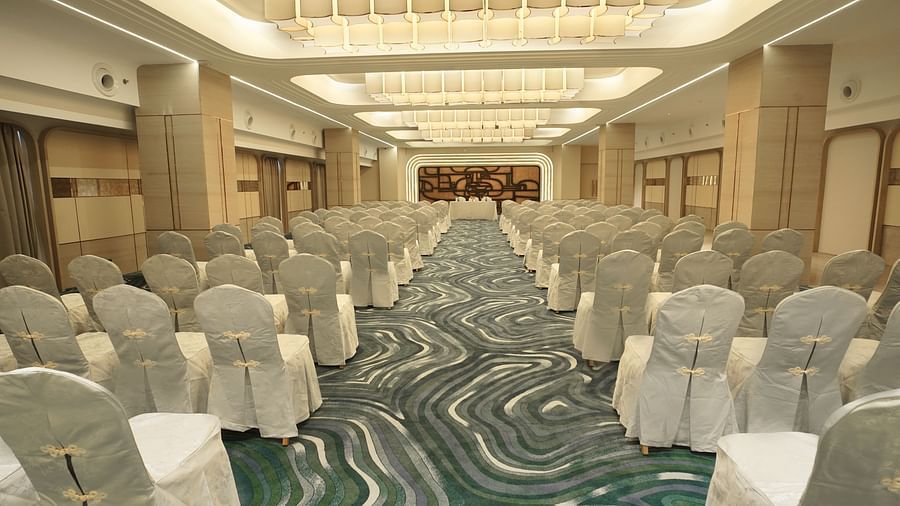 Spacious venue prepared for an event with rows of white-covered chairs. Patterned floor and bright overhead lighting - The Orchid Hotel, Chandigarh