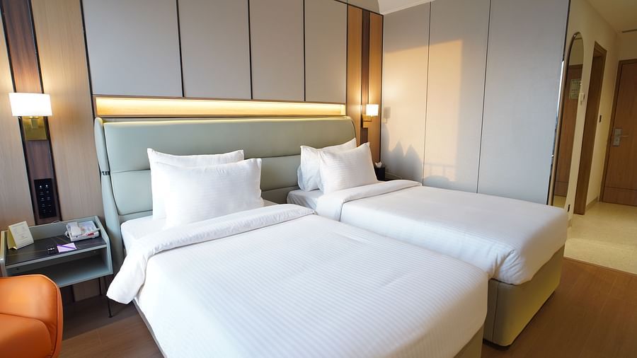 A comfortable hotel club room displays a king-sized bed with white bedding, a bedside table with a lamp, and a partial view of the rooms decor -  The Orchid Hotel, Chandigarh
