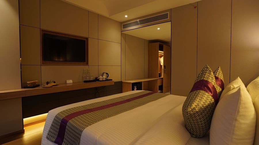 A well-appointed hotel club room offers a view of the bed with decorative pillows, a wall-mounted TV, a desk area, and warm ambient lighting - The Orchid Hotel, Chandigarh