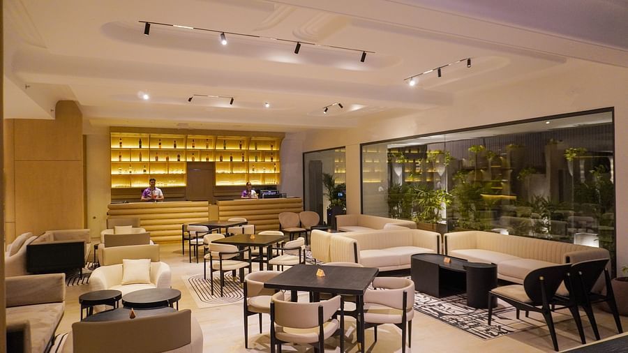 Contemporary hotel dining space with elegant dark wood tables, comfortable upholstered chairs, and expansive windows offering natural light - The Orchid Hotel, Chandigarh