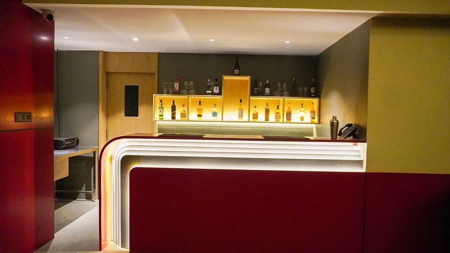 Stylish indoor bar area at Skydip, featuring a sleek white countertop with red accents and warm, inviting backlighting showcasing various bottles - The Orchid Hotel, Chandigarh