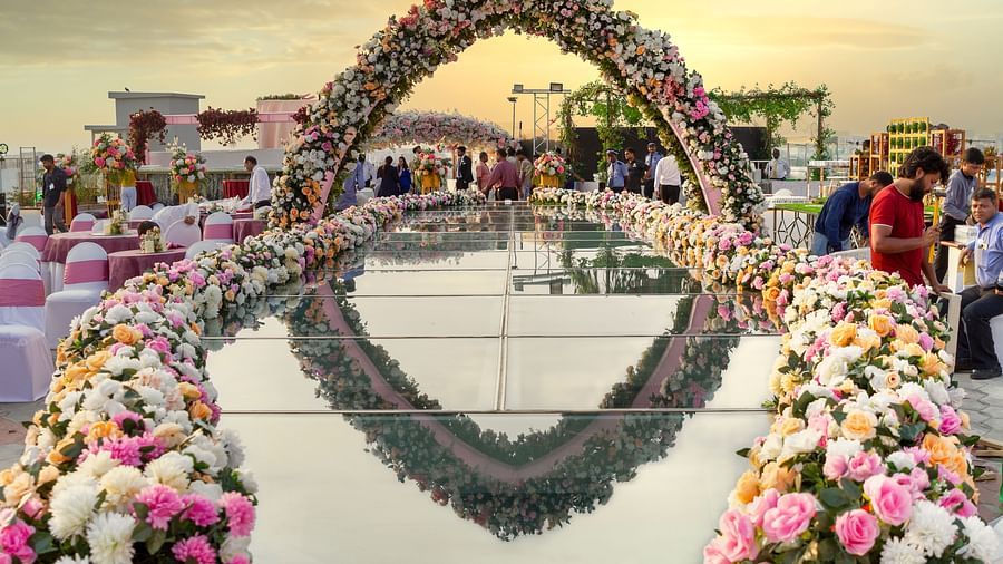 Outdoor wedding ceremony setup at The Orchid Hotel rooftop, decorated with a floral arch and mirrored walkway, overlooking the sunset skyline, providing a romantic setting.