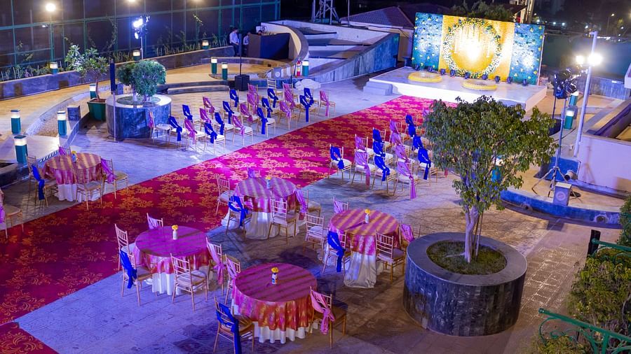 Night view of an outdoor event space at The Orchid Hotel, featuring colorful seating arrangements and decorative lighting, ready for an evening social event.