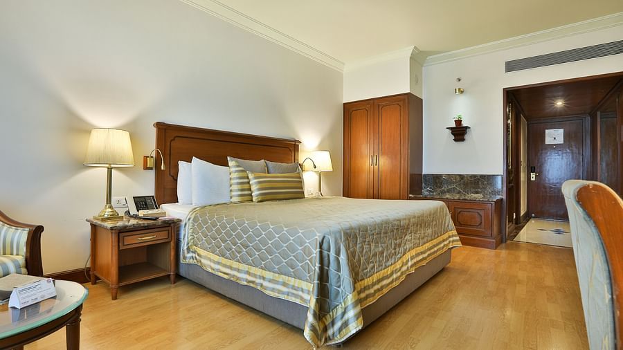 room with a cosy king size bed and wooden flooring - The Orchid Hotel Mumbai Vile Parle
