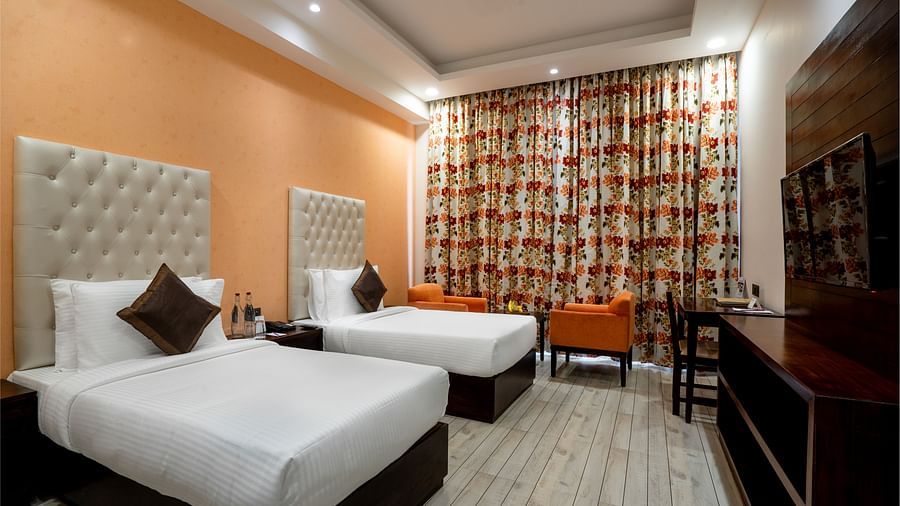 A lovely bedroom featuring twin beds facing a flat screen TV - The Orchid Hotel Shimla