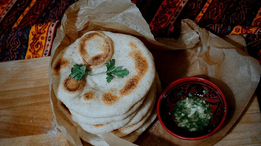 an image of  a series of fluffy, golden-brown kulchas neatly placed on a surface with butter 