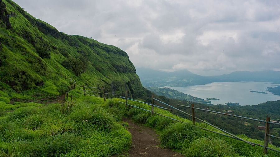 A path going up a grassy hill with mountains in the background.
