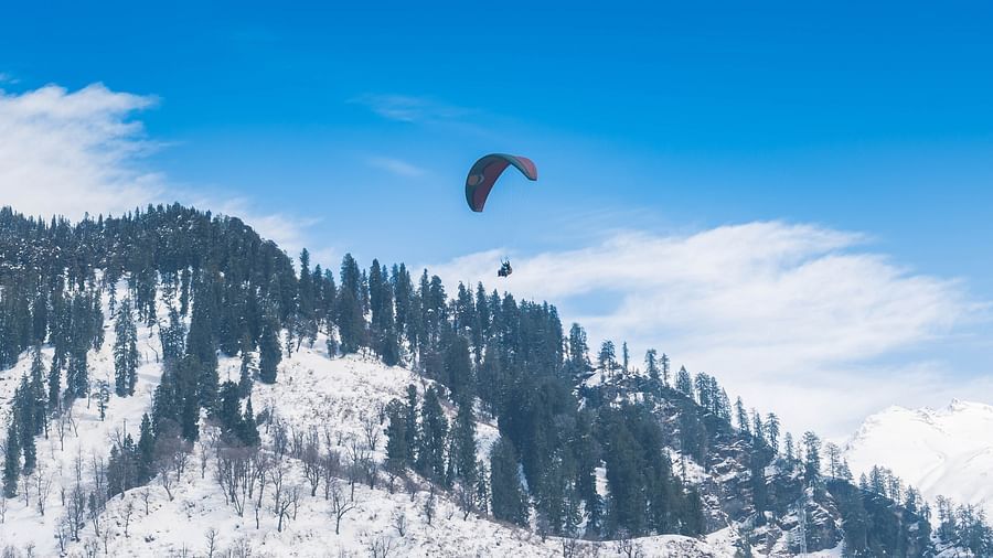A person paragliding amidst the snow capped mountains