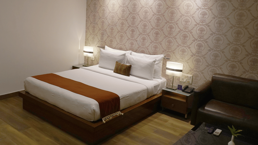 The plush king size bed of the Junior Suite at Sarovar Portico, Bhubaneswar, highlighted under ample overhead lighting.
